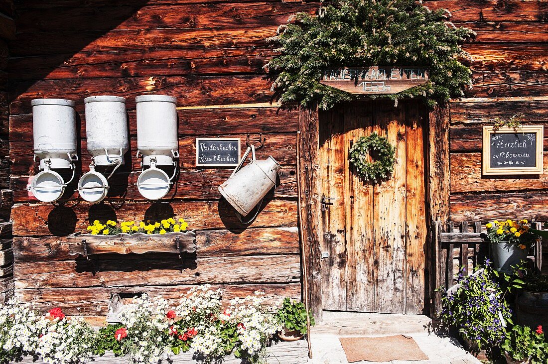 Alpine cabin with milk churns and decorative flower pots (Austria)