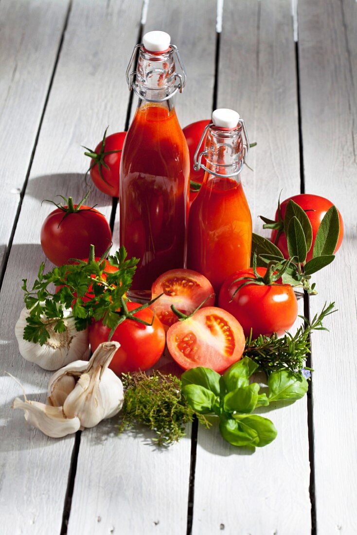 Tomatenstilleben mit Tomatensaft, Tomaten und frischen Kräutern