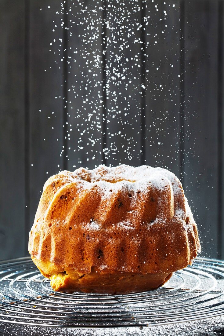 A birthday Bundt cake being dusted with icing sugar