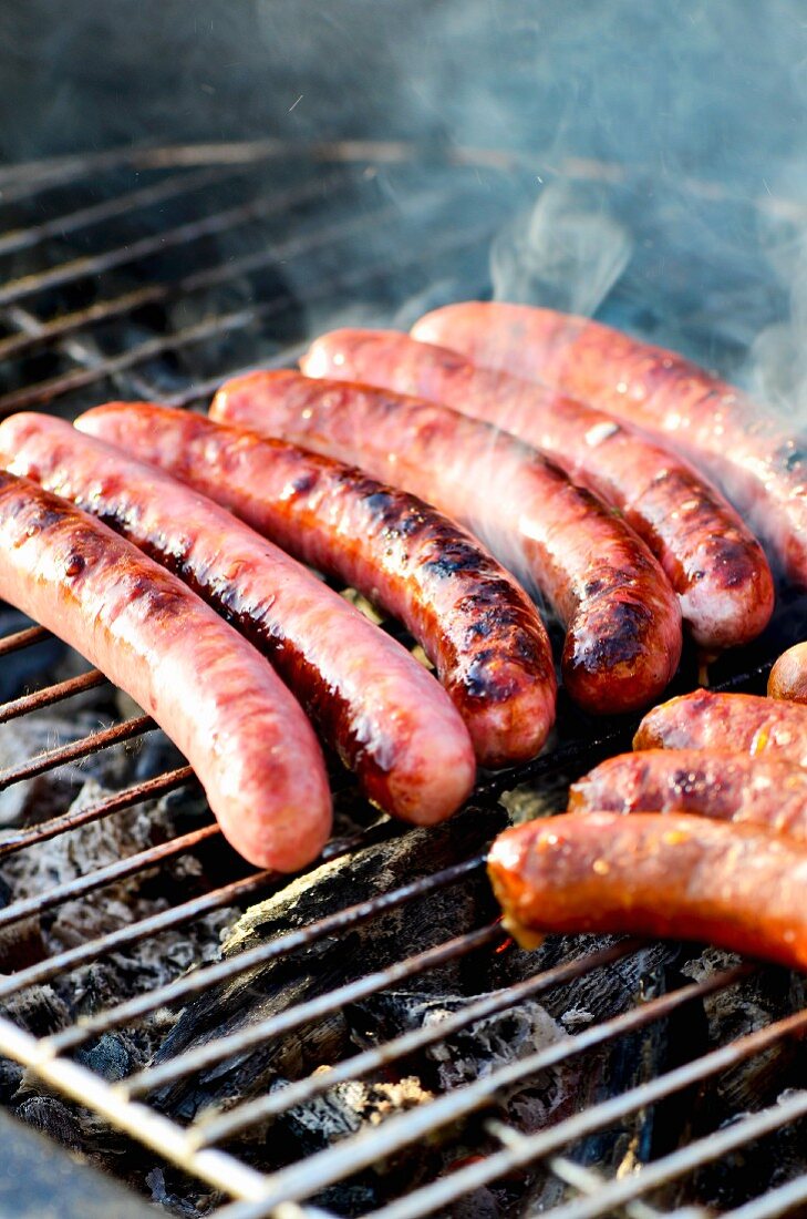 Chipolata sausages on a smoking barbecue