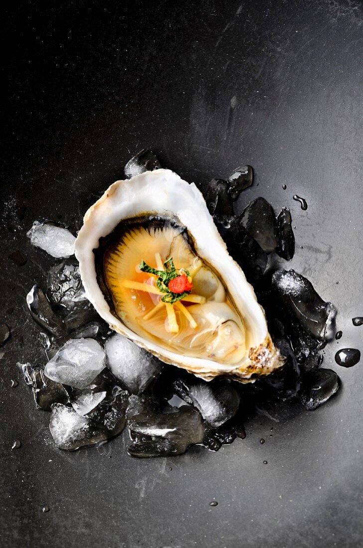 An oyster with ginger, miso and chilli on ice cubes
