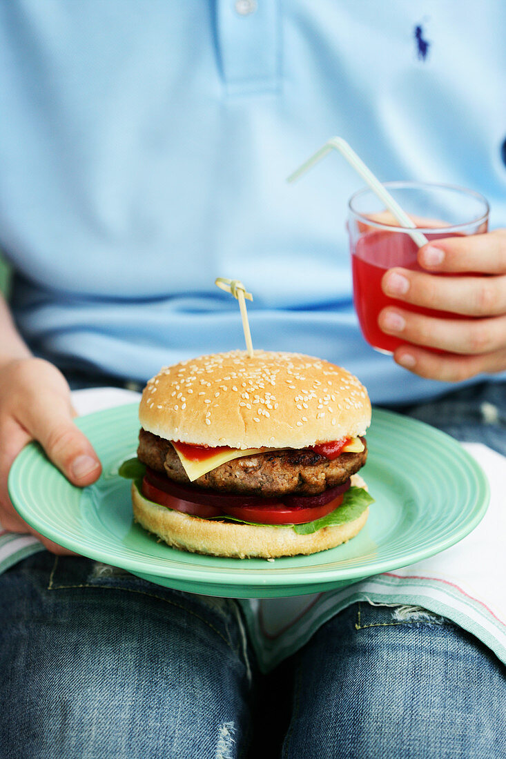 Kind hält Teller mit Cheeseburger