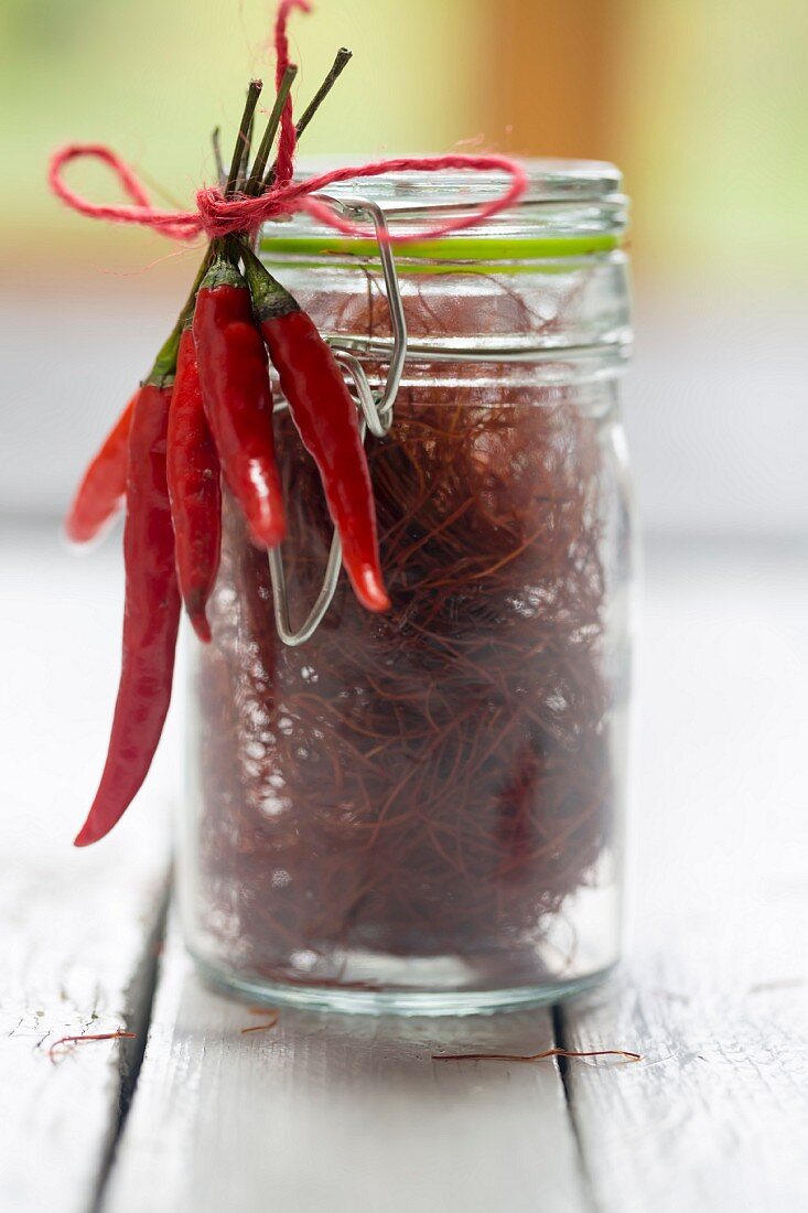 Chilischoten an einem mit Chilifäden gefüllten Glas