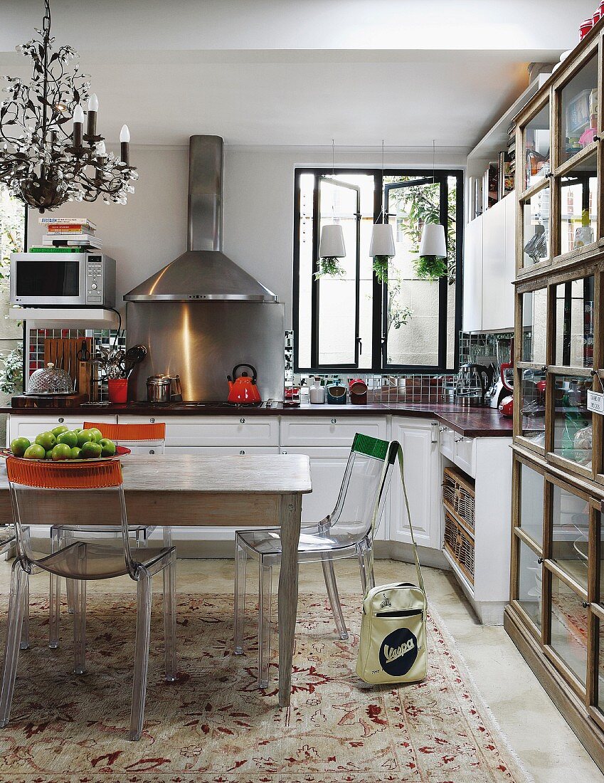 Transparent plastic chairs with colourful stripes on backrests around wooden table in white, country-house kitchen