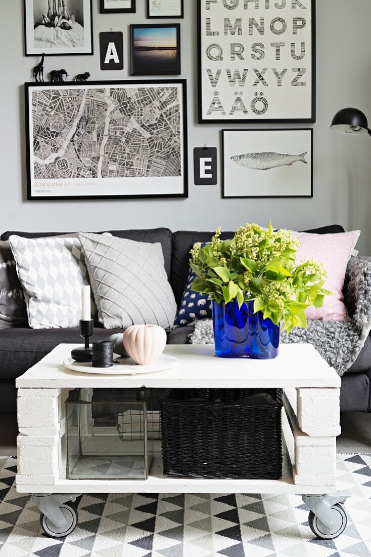 Weissgrauer Sitzplatz mit Sofa und königsblaue Glasvase als Hingucker auf rollendem DIY Coffeetable, Bildergalerie im Hintergrund