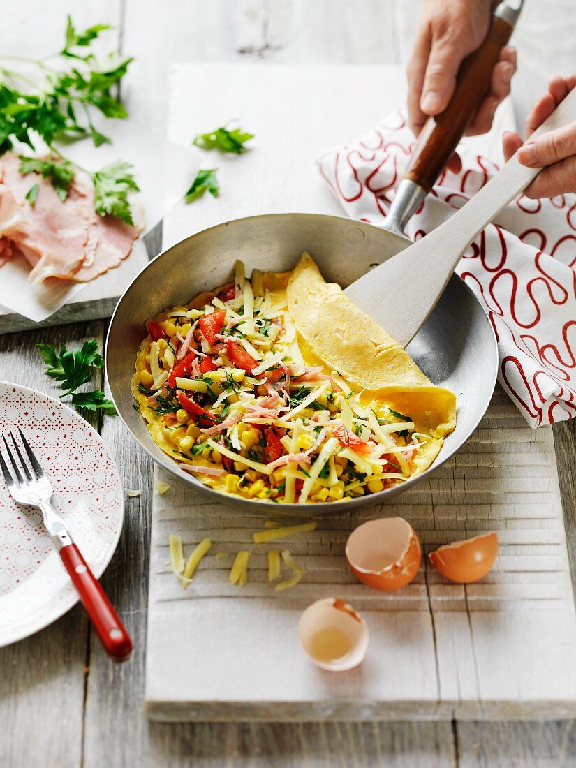 Omelette with ham, sweetcorn and cheese in a pan