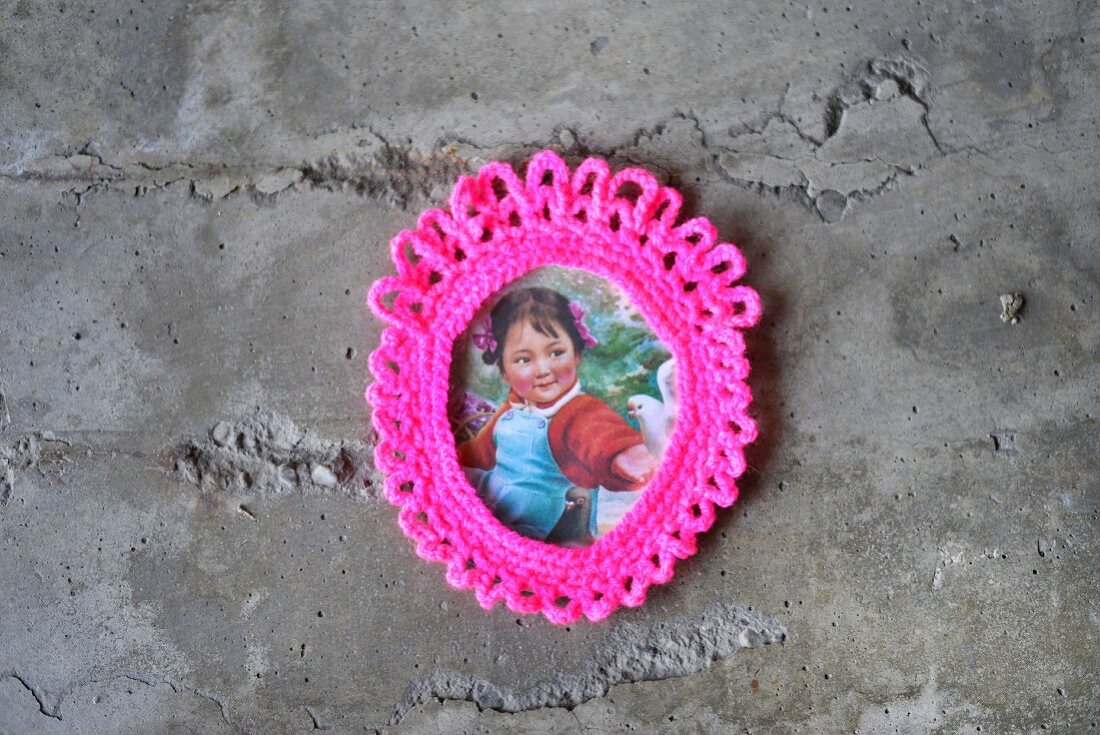 Vintage picture of little girl in neon pink crocheted frame on concrete wall