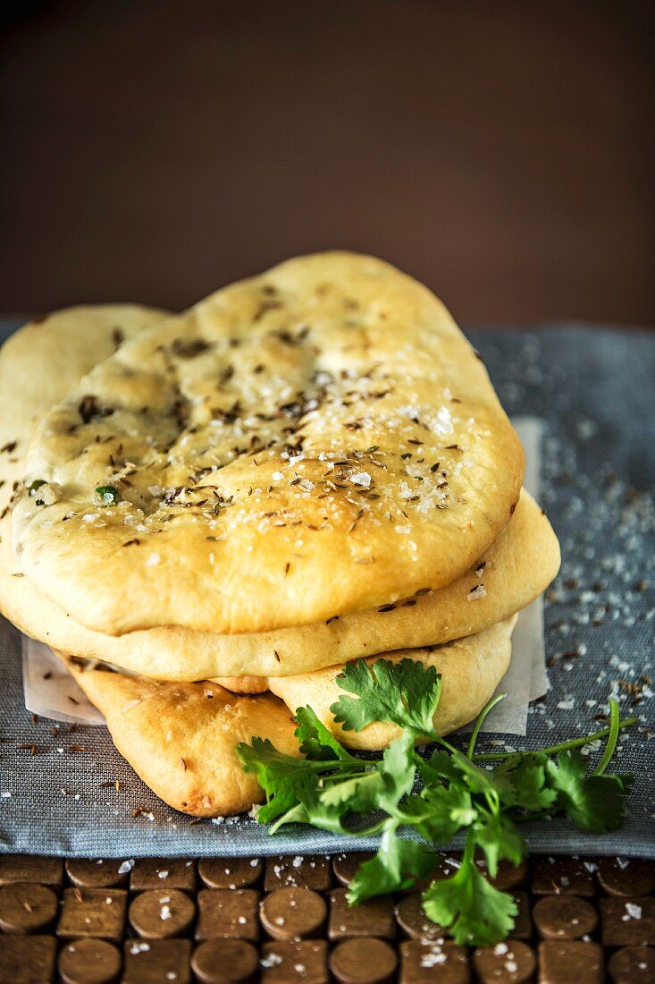 A stack of naan breads with a potato filling and cumin seeds