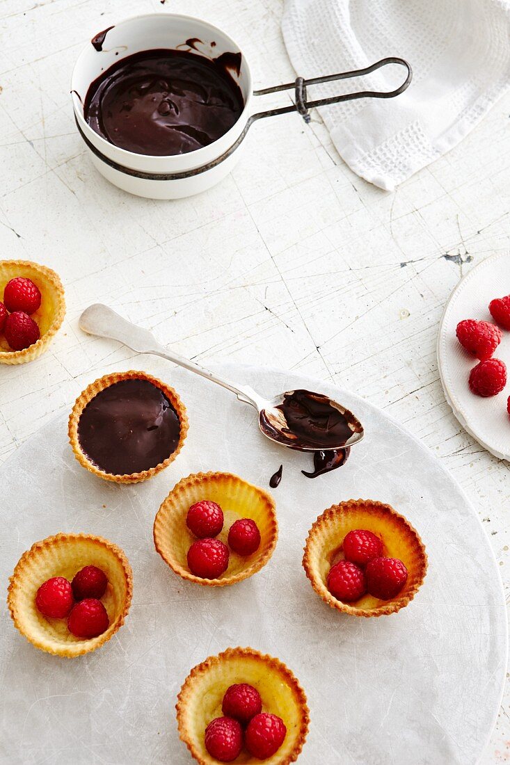 Chocolate tartlets with raspberries being made