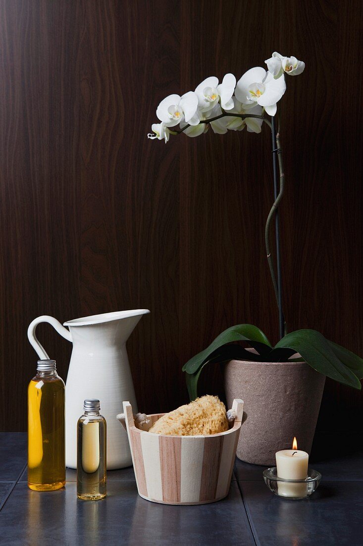 Spa Deko mit Orchideentopf, Krug, Schwamm in Mini-Bottich und Glasflaschen mit Badeöl