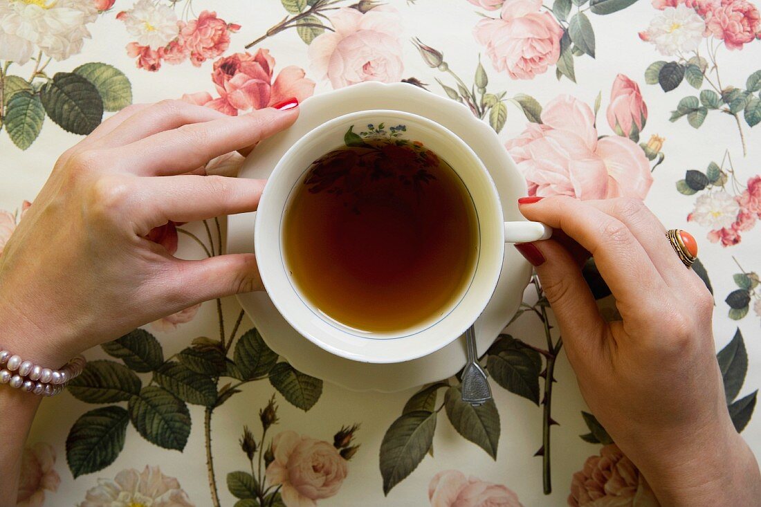 Frauenhände halten eine Teetasse