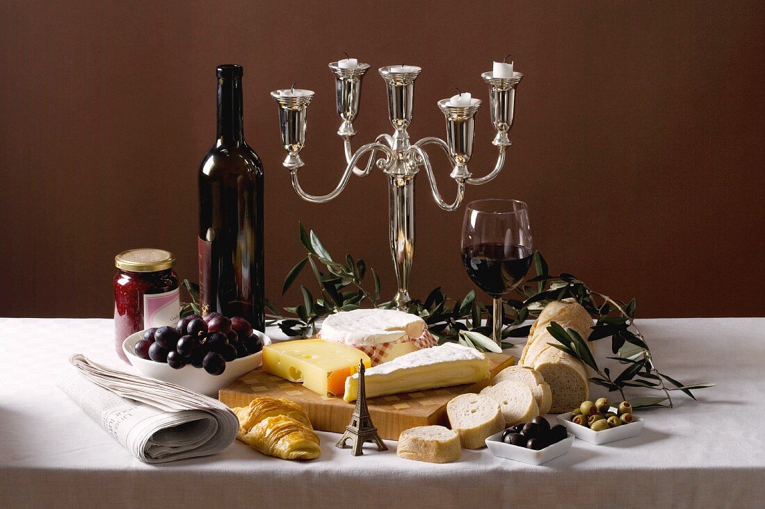 Various types of cheese with baguette, olives, grapes and red wine from France