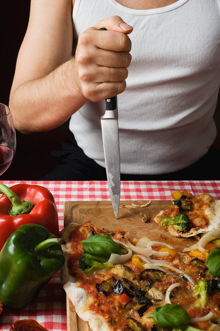 Typisch italienischer Mann sticht Messer in Schneidebrett neben Pizza