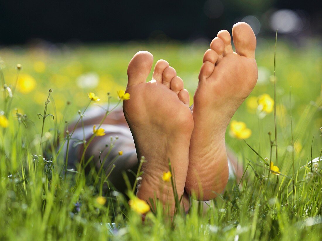 Nackte Fusssohlen einer im Gras liegenden Person