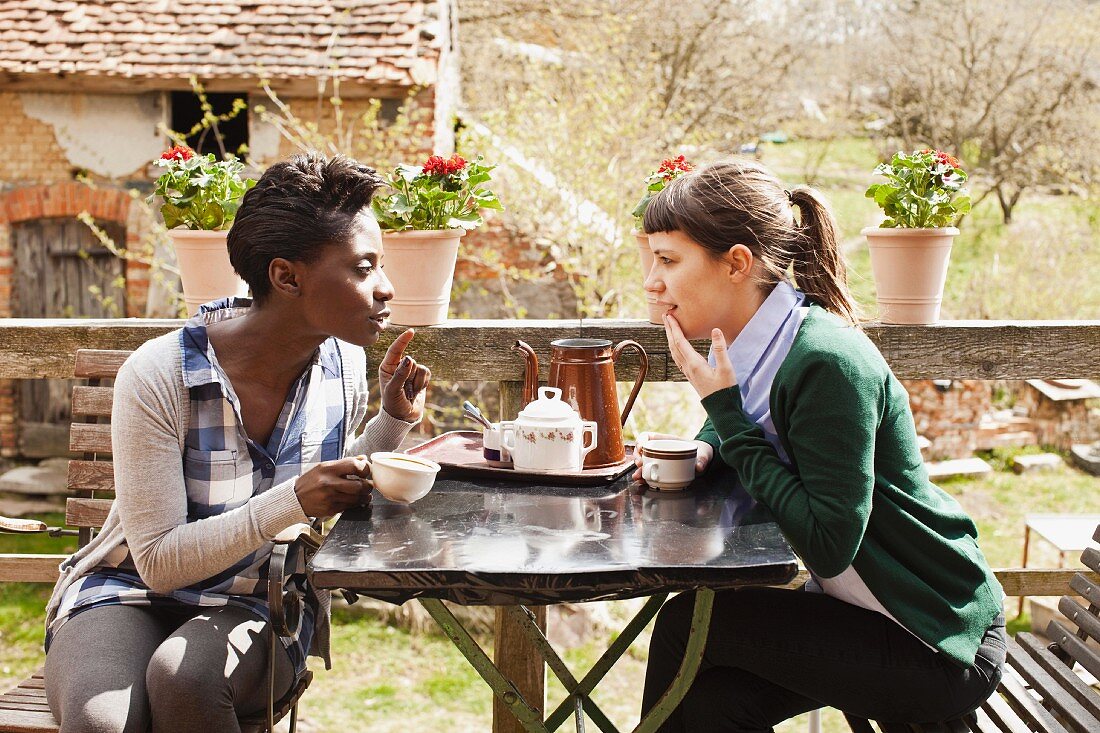 Two women having coffee and a chat in a garden