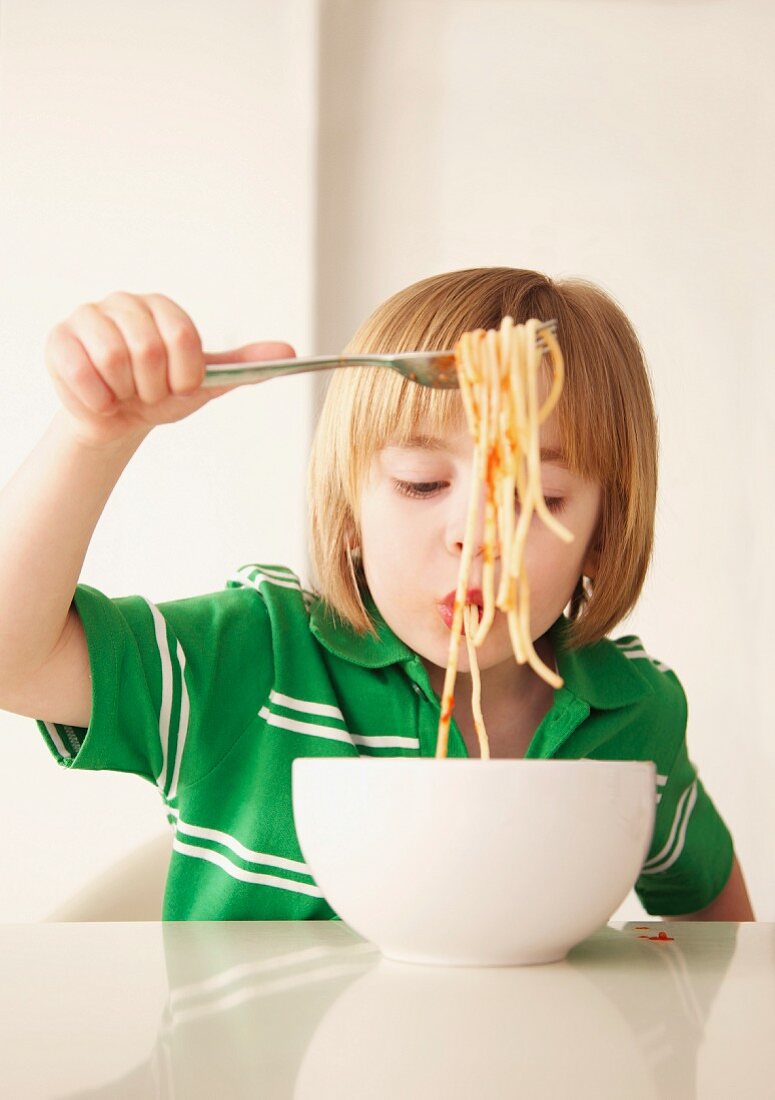Junge isst Spaghetti mit Tomatensauce