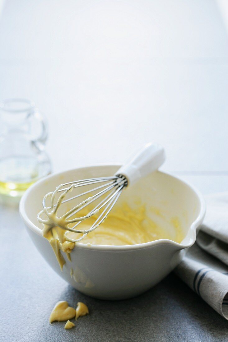 A bowl of mayonnaise with a whisk