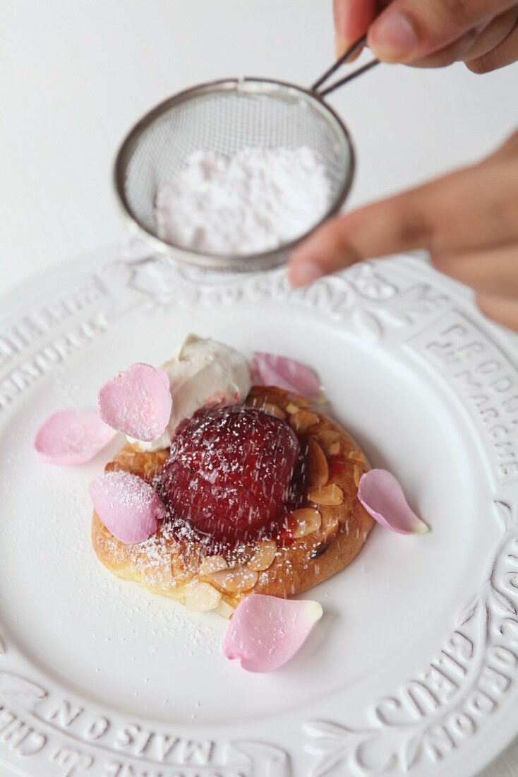 A plum desert being dusted with icing sugar