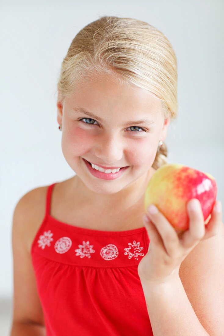 Lächelndes blondes Mädchen hält einen Apfel