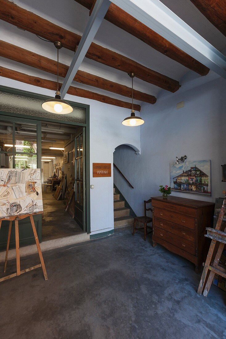 Simple room with wood-beamed ceiling and picture on easel in front of glass partition