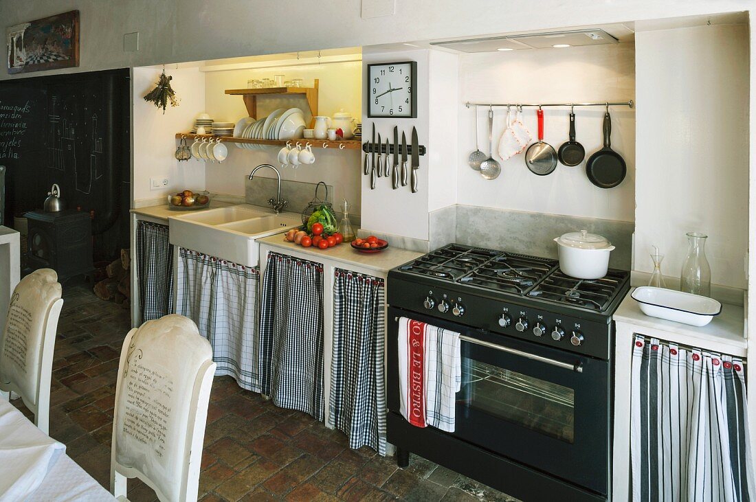 Simple kitchen counter with curtains on base units flanking gas cooker