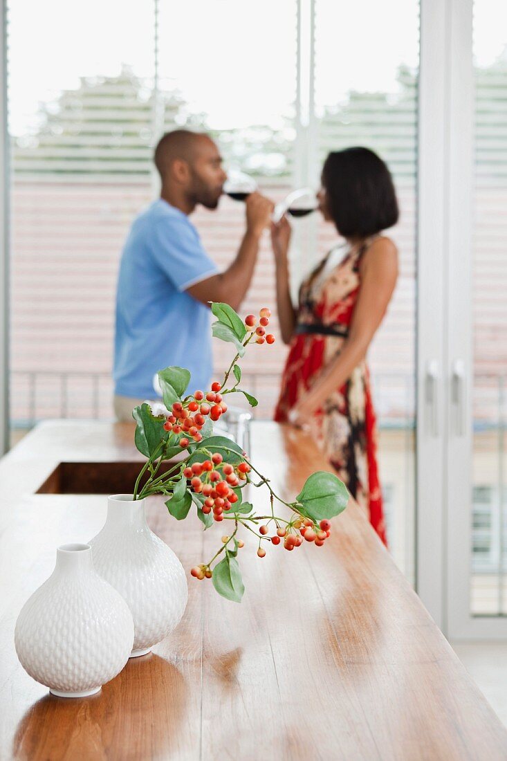 Arbeitsfläche in Küche mit Vasen, Paar trinkt Wein im Hintergrund
