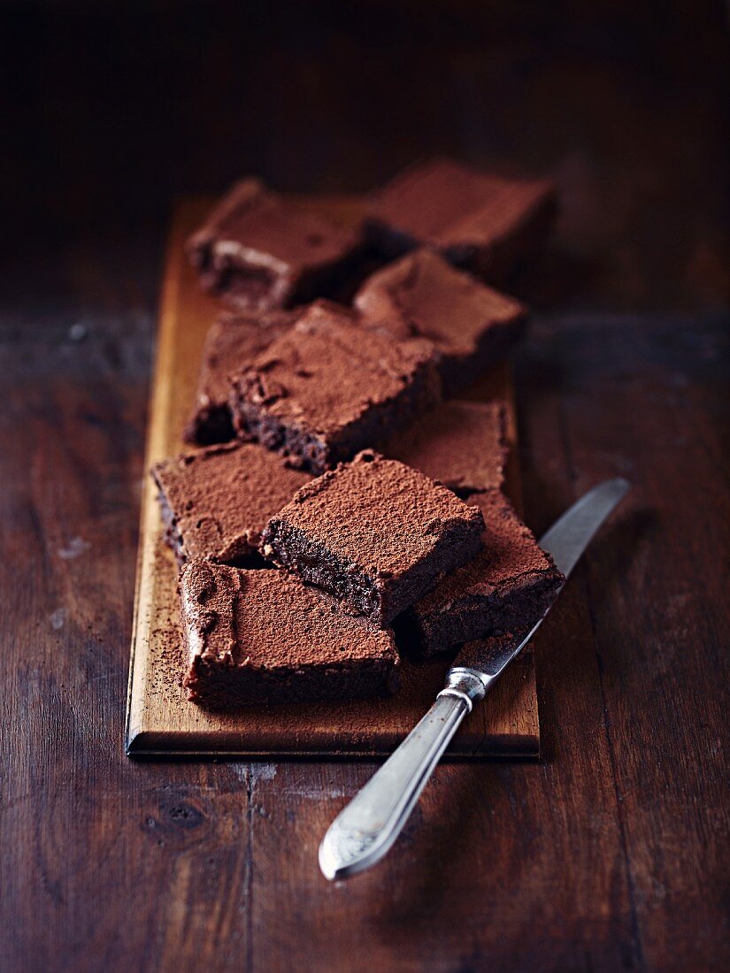 Rustic chocolate brownies on a wooden board with a knife