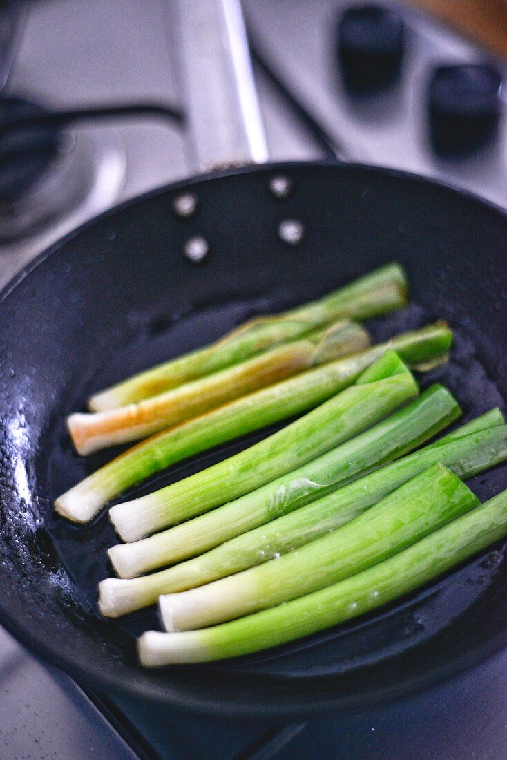 Leek being fried in a pan