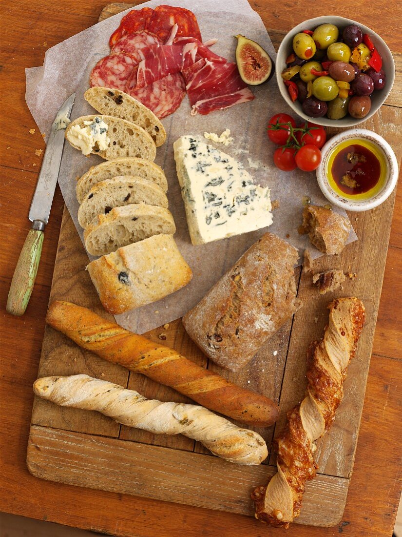 Various types of bread, blue cheese, salami, olives and olive oil