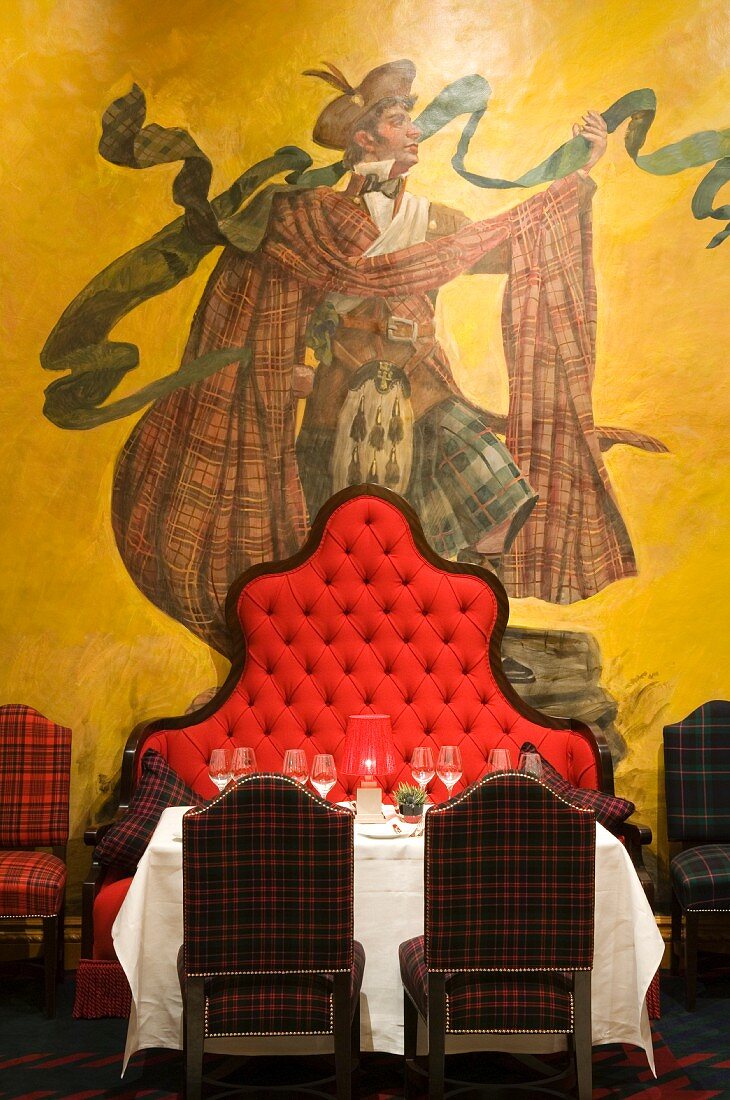 Mural of highland Scot behind set table and bench with tall, curved backrest in the Dorchester Hotel, London