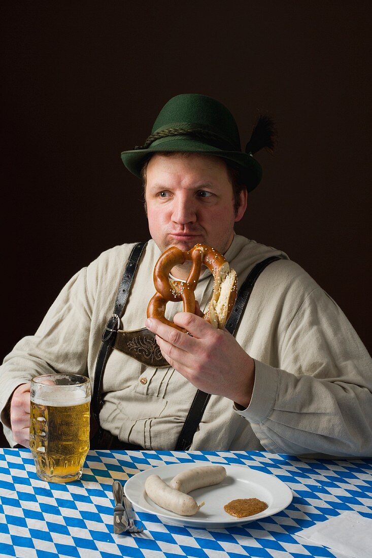 Typisch bayerischer Mann in Tracht mit Bier, Brezel und Weisswurst