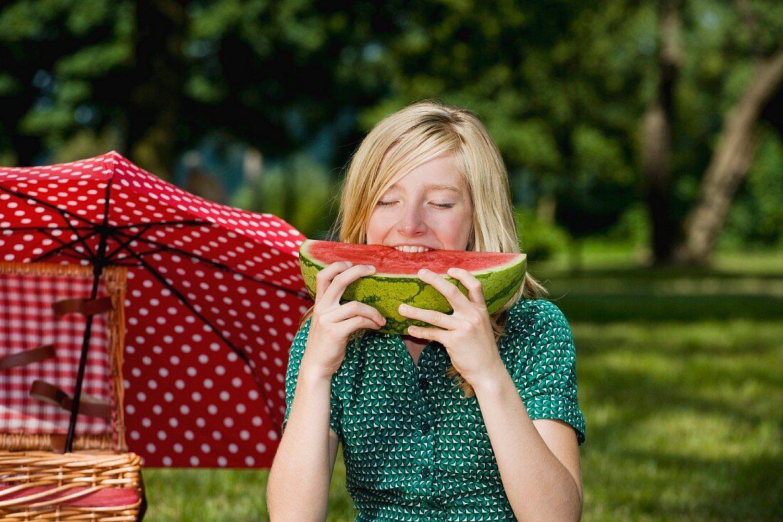 Mädchen isst ein Stück Wassermelone beim Picknick