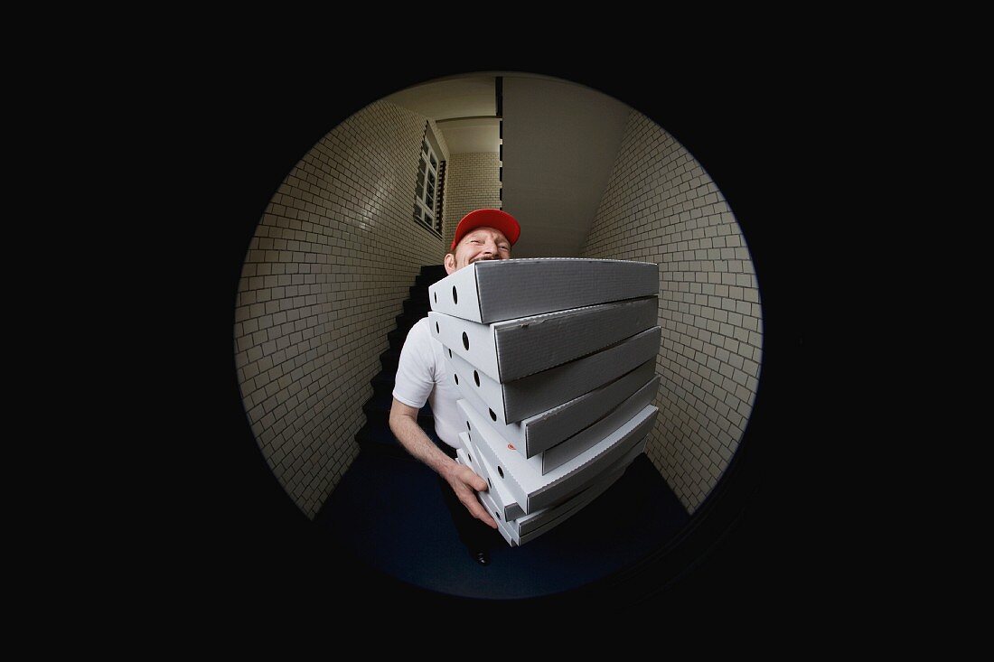 Pizzabote mit gestapelten Pizzakartons im Türspion