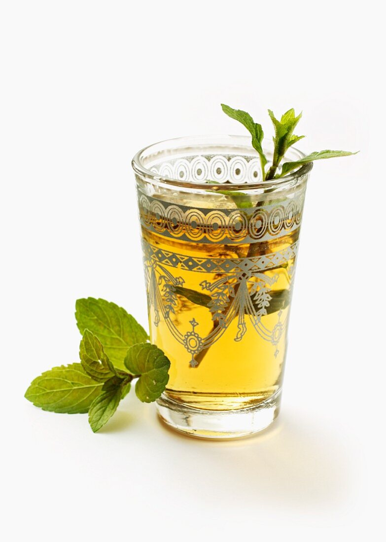 A glass of peppermint tea garnished with a sprig of mint