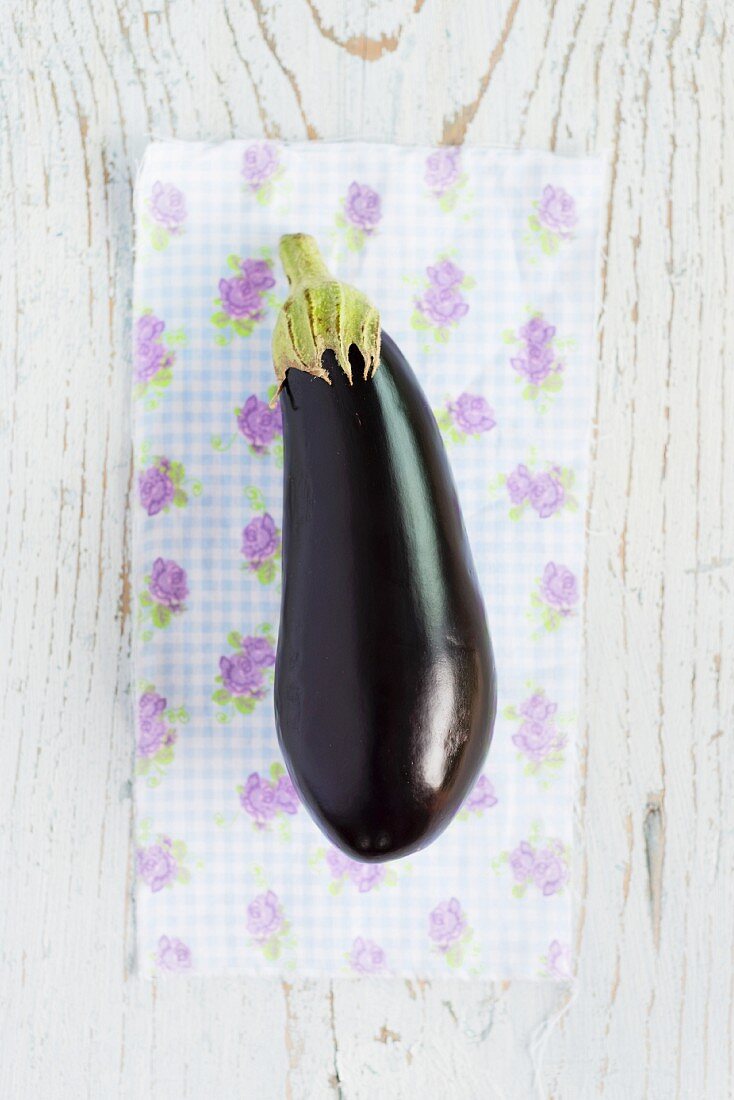 Eine Aubergine auf geblümtem Tuch