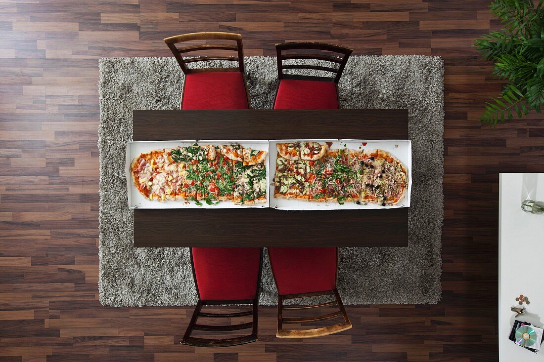 Two large pizzas side by side on a dining table (seen from above)