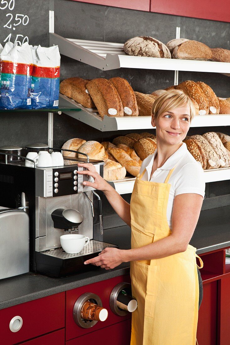 A sales assistant using an espresso machine in a bakery
