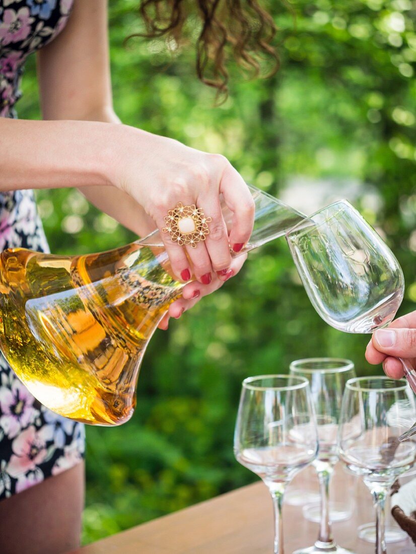 Frau giesst georgischen Kvevri-Weißwein zur Degustation aus Dekantierkaraffe in Gläser