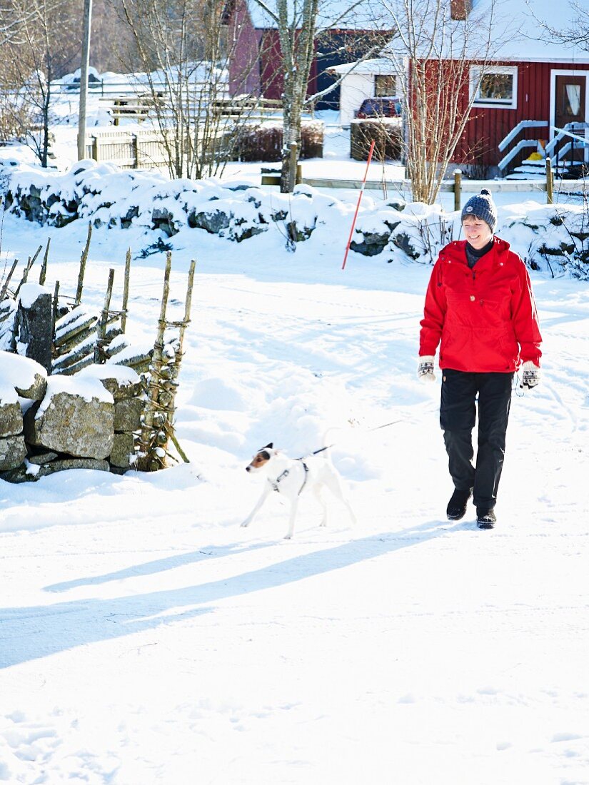 Woman and dog on snowy street in Scandinavia