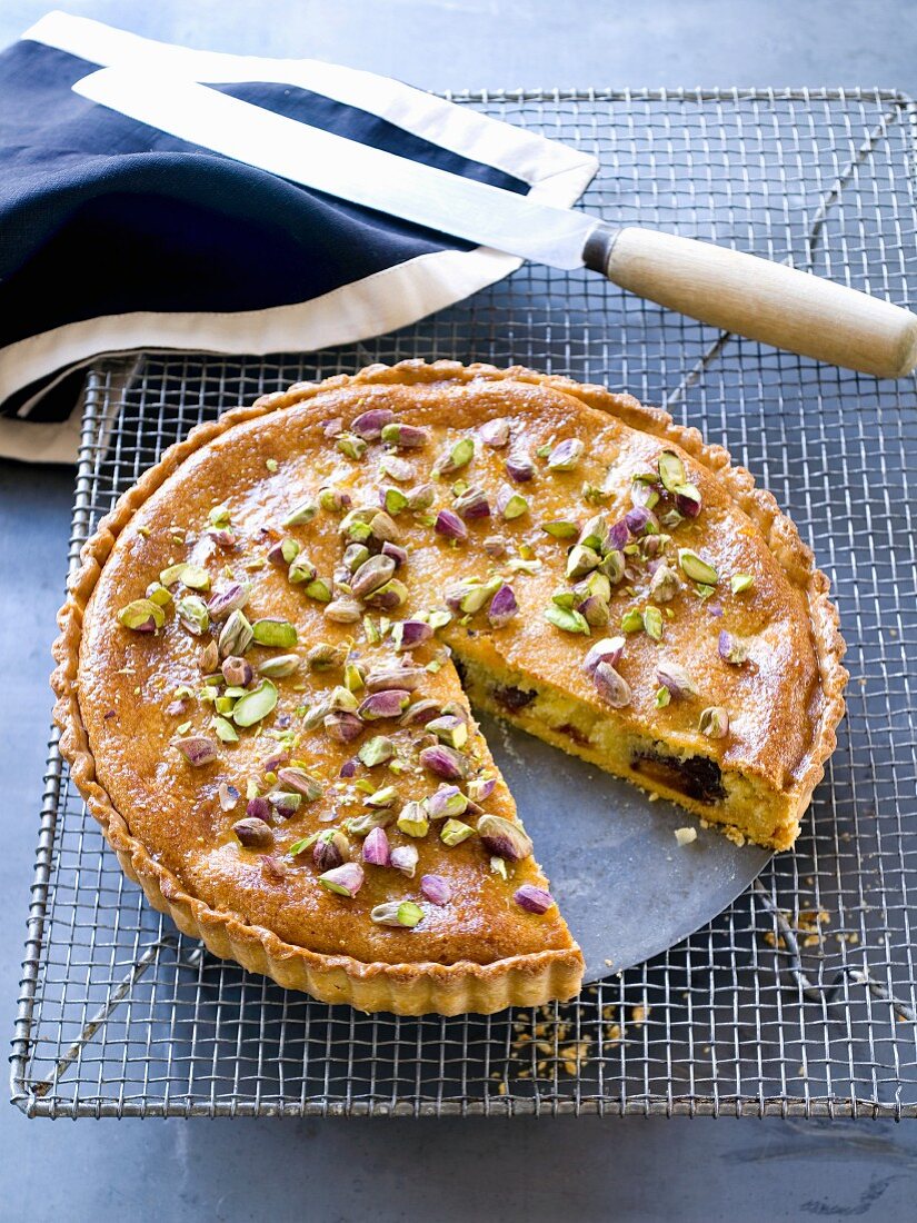 An almond and date tart with pistachios, sliced