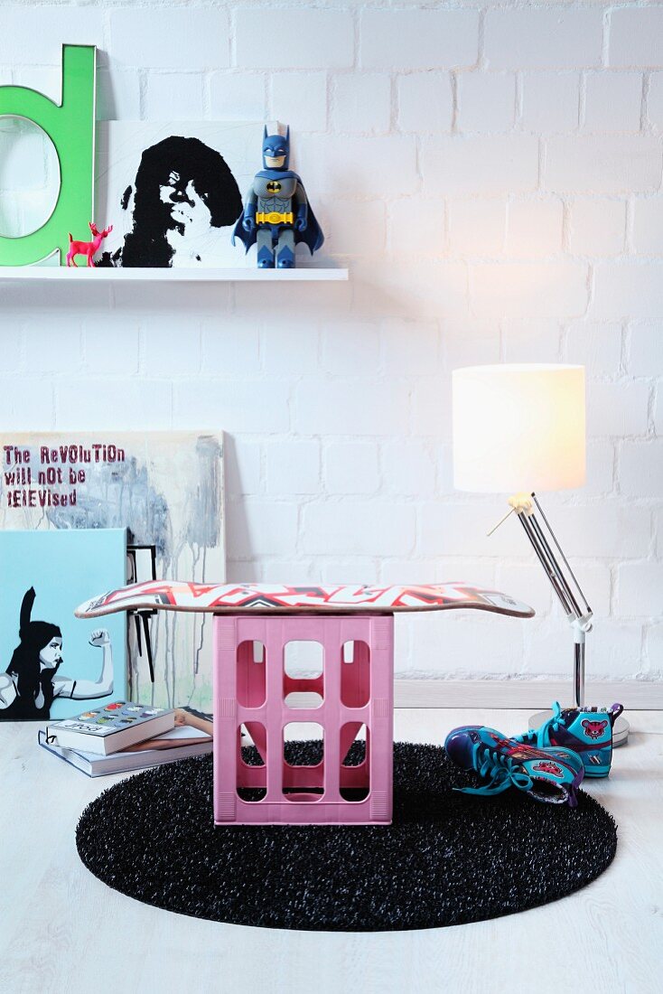 DIY stool made from skateboard bolted to pink drinks crate