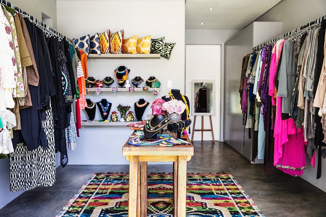 Walk-in feminine wardrobe with jewellery racks on narrow wooden table in modern interior