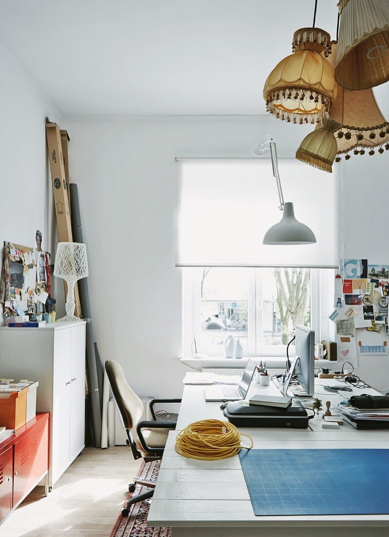 Workspace with collection of lampshades in apartment of young, designer couple