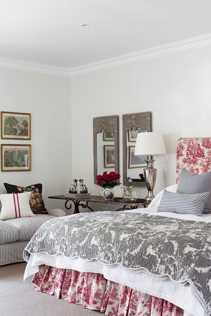 Bedroom in traditional, French style with toile de jouy textiles and classic lamp on antique side table