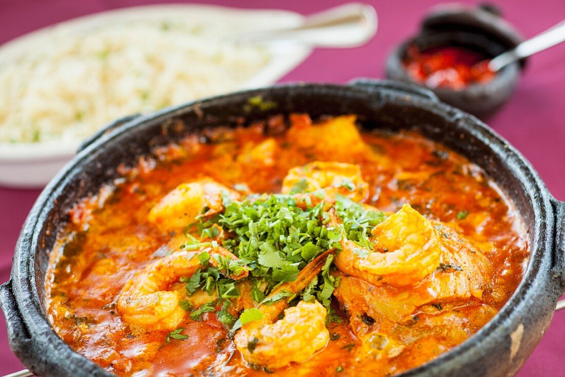 Moqueca (Brazilian stew with fish and prawns) in a terracotta pot with rice in the background