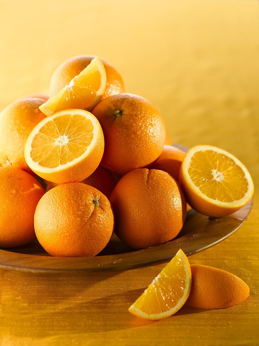 Oranges, whole and halved, in a wooden bowl