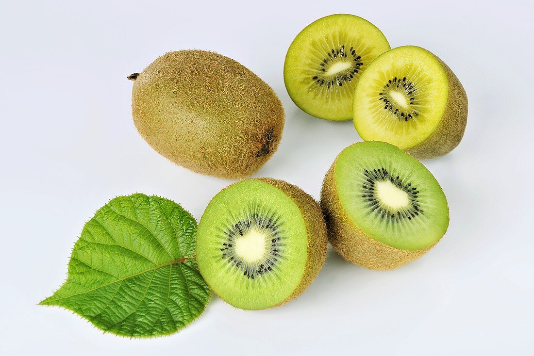 Green and yellow kiwis, whole and halved and with a leaf