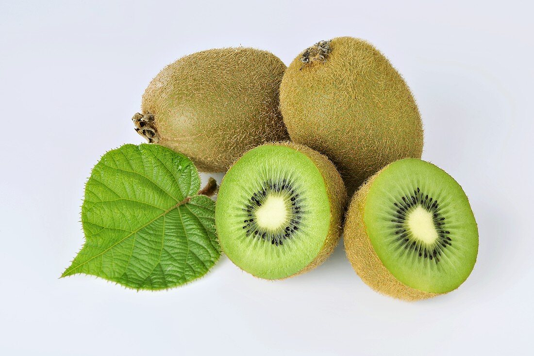 Green kiwis, whole and halved and with a leaf