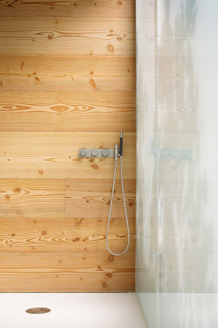 Shower with fittings on a wood panel wall
