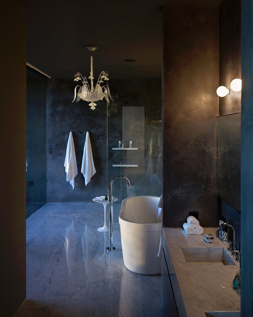Goldene, filigrane Hängeleuchte in edlem, dunklem Designerbad mit spiegelndem Boden und Waschtisch aus Marmor